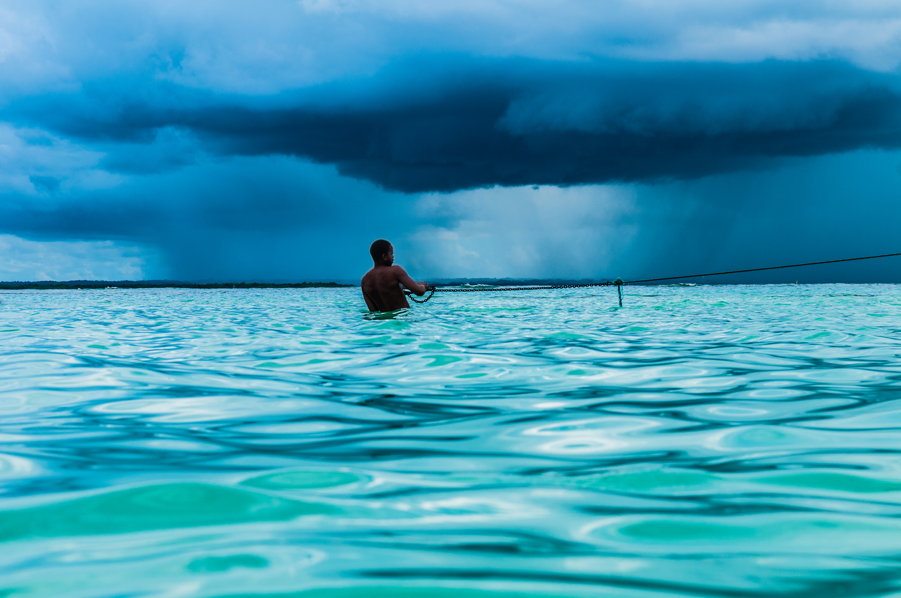 France, Caraïbes, Petites Antilles, Guadeloupe, Grand Cul-de-Sac marin, homme tentant d'amarrer son bateau aux abords de l'îlet Caret, sur fond de pluie tropicale // France, Caribbean, Lesser Antilles, Guadeloupe, Grand Cul-de-Sac marin, man trying to moor his boat near the islet Caret, a tropical rain in the background