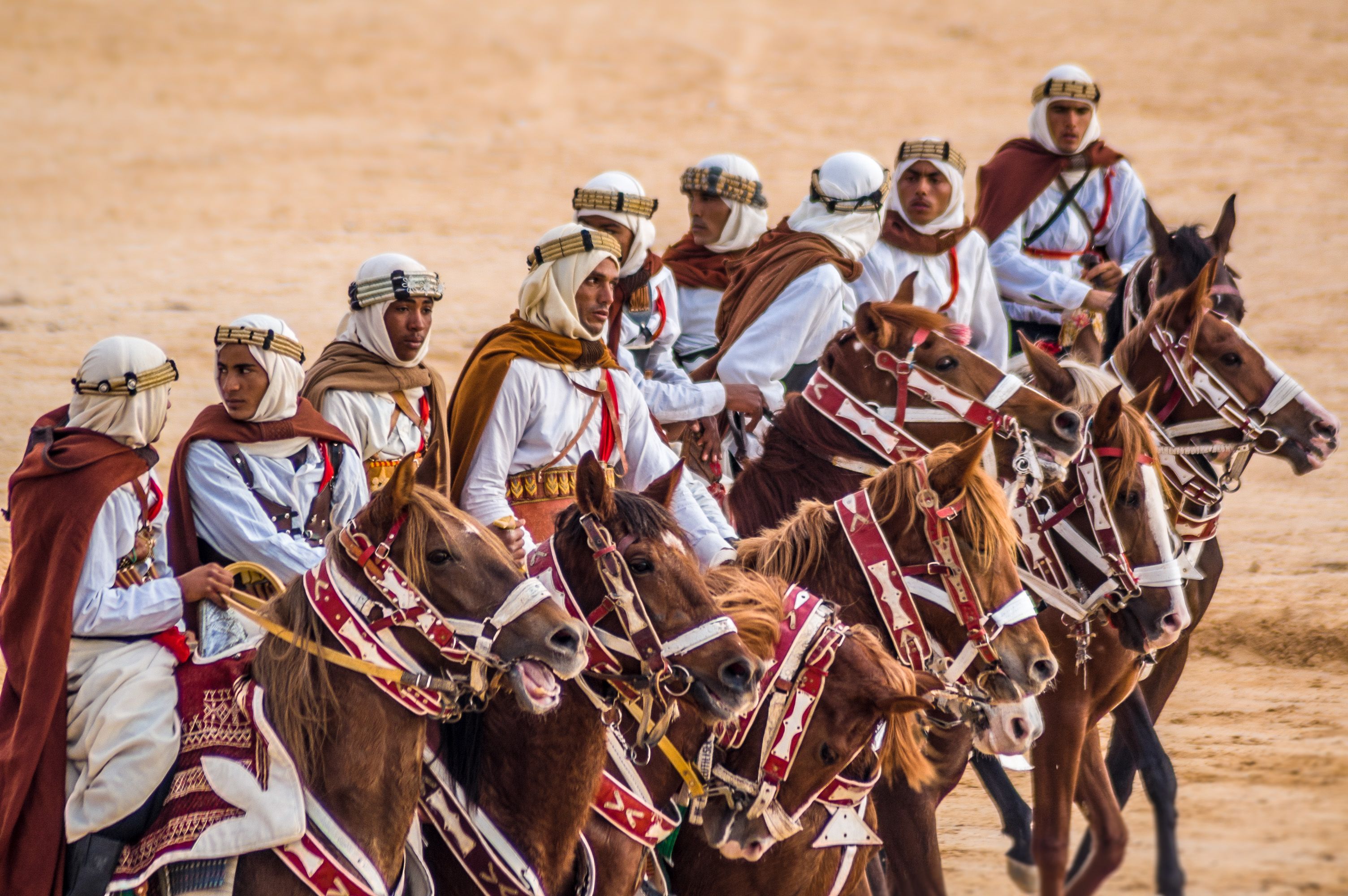 Riders on Arab stallions parade wearing their traditional outfits from the southern Douz region, seen, during the opening of the Sahara International Festival in Douz, southwestern Tunisia. The International Sahara Festival in the city of Douz draws locals and tourists alike for a cultural event that celebrates the region's heritage and desert people / Cavaliers en habits traditionnels sur des pur sang arabes au Festival International du Sahara de Douz, Tunisie. Le Festival, qui attire touristes et locaux, célèbre les peuples du désert et l'héritage régional.