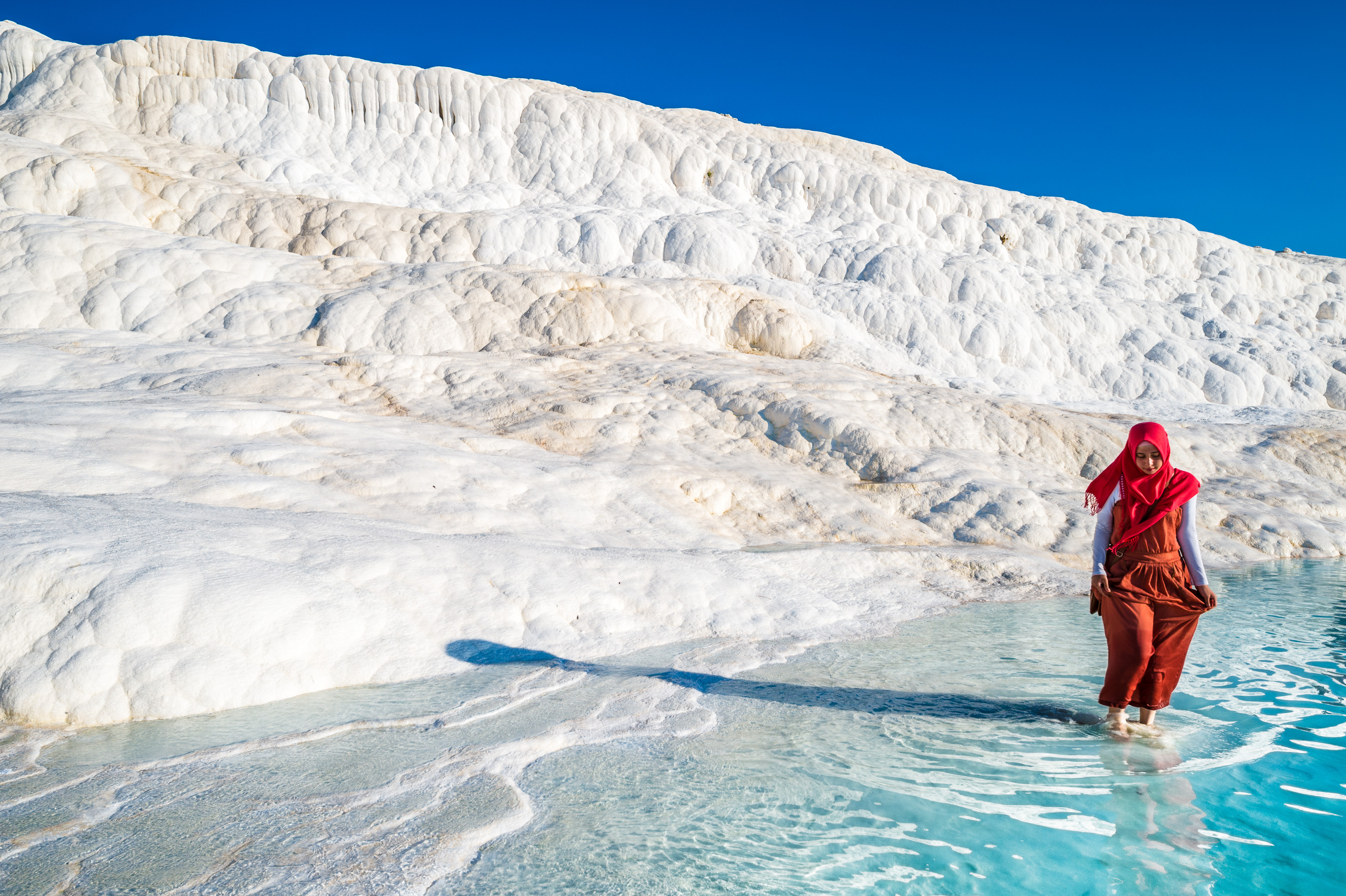 Turquie, région Égéenne, province de Denizli, Pamukkale (château de coton) et la cité antique de Hierapolis inscrits au patrimoine mondial de l'Humanité par l'UNESCO, femme trempant les pieds dans une des piscines naturelles géothermales entourées de concrétions calcaires à l'entrée du site de Pamukkale, PR // Turkey, Aegean Region, Denizli Province, Pamukkale (Cotton Castle) and the Ancient City of Hierapolis World Heritage Site by UNESCO, woman dipping her feet in one of the natural geothermal pools surrounded by limestone concretions not far after the entry to the Pamukkale site, PR