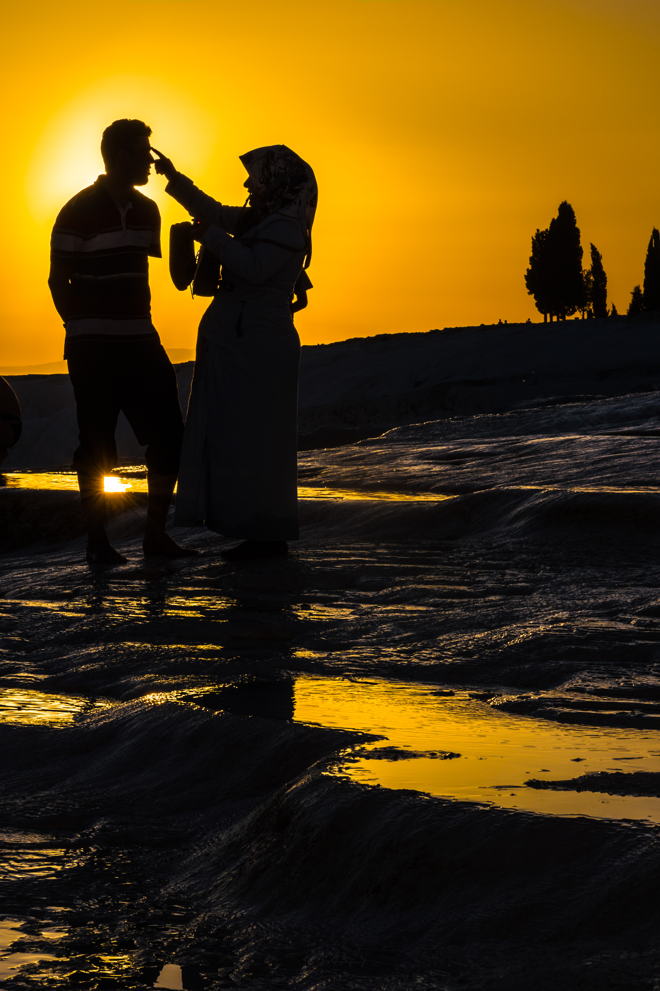 Turquie, région Égéenne, province de Denizli, Pamukkale (château de coton) et la cité antique de Hierapolis inscrits au patrimoine mondial de l'Humanité par l'UNESCO, silhouettes d'un couple se promenant parmi les bassins de travertin blanc aux eaux géothermales entourés de concrétions calcaires, au coucher du soleil, PR // Turkey, Aegean region, Denizli province, Pamukkale (cotton castle) and the ancient city of Hierapolis, UNESCO World Heritage Site, silhouettes of a couple wandering among the basins of white travertine with geothermal waters surrounded by calcareous concretions, at sunset, PR