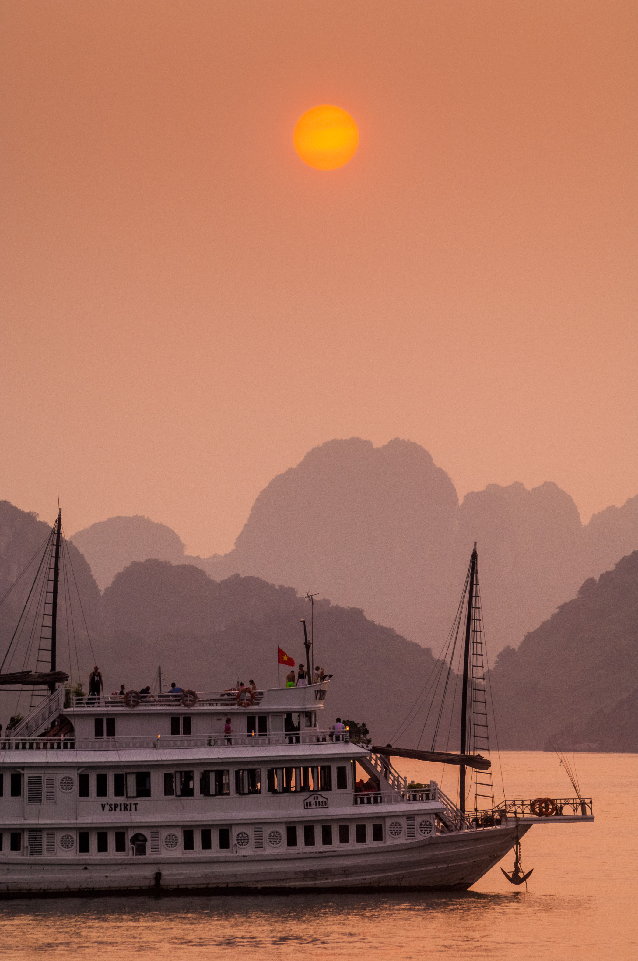 Asie du Sud-Est, Viêt Nam, golfe du Tonkin, Province de Quảng Ninh, Baie d'Ha-Long (Vịnh Hạ Long) inscrite au Patrimoine mondial de l'Unesco (1994), coucher du soleil sur un sampan touristique au milieu du paysage emblématique aux reliefs karstiques // Southeast Asia, Vietnam, Gulf of Tonkin, Quang Ninh province, Ha Long Bay (Vinh Ha Long) on the UNESCO World Heritage (1994), sunset on a tourist sampan amid the iconic landscape of karst landforms