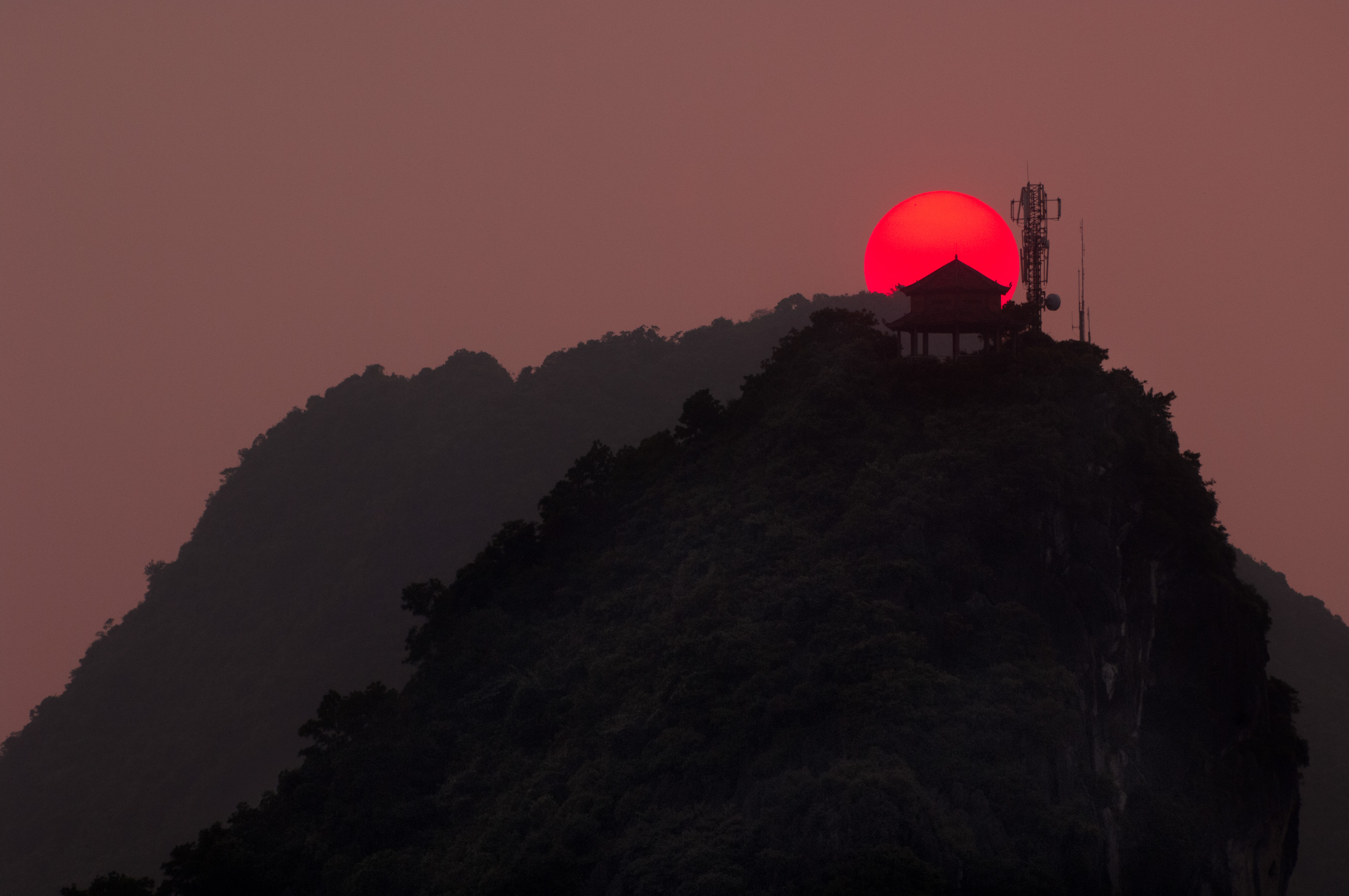 Asie du Sud-Est, Viêt Nam, golfe du Tonkin, Province de Quảng Ninh, Baie d'Ha-Long (Vịnh Hạ Long) inscrite au Patrimoine mondial de l'Unesco (1994), coucher du soleil sur le paysage emblématique aux reliefs karstiques surmontés d'un abri en forme de pagode // Southeast Asia, Vietnam, Gulf of Tonkin, Quang Ninh Province, Ha Long Bay (Vinh Ha Long) on the UNESCO World Heritage (1994), sunset on the iconic landscape of karst landforms topped with a pagoda shaped shelter