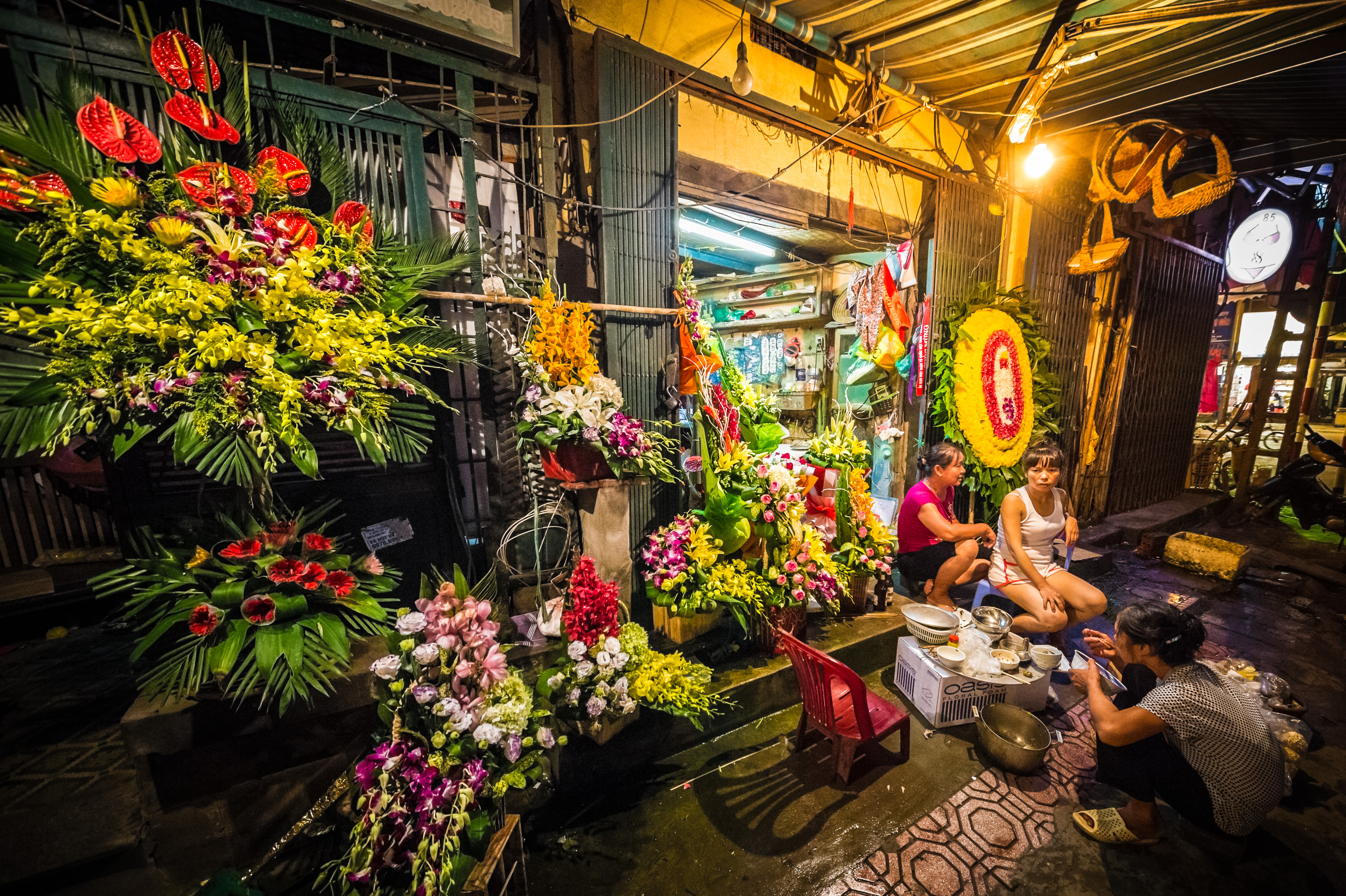 Asie du Sud-Est, capitale du Viêt Nam, delta du fleuve Rouge, ville de Hanoï, femmes fleuristes dînant sur le trottoir devant leur échoppe, de nuit // Southeast Asia, Vietnam's capital, Red River Delta, Hanoi, florists women dining on the sidewalk in front of their shops, by night