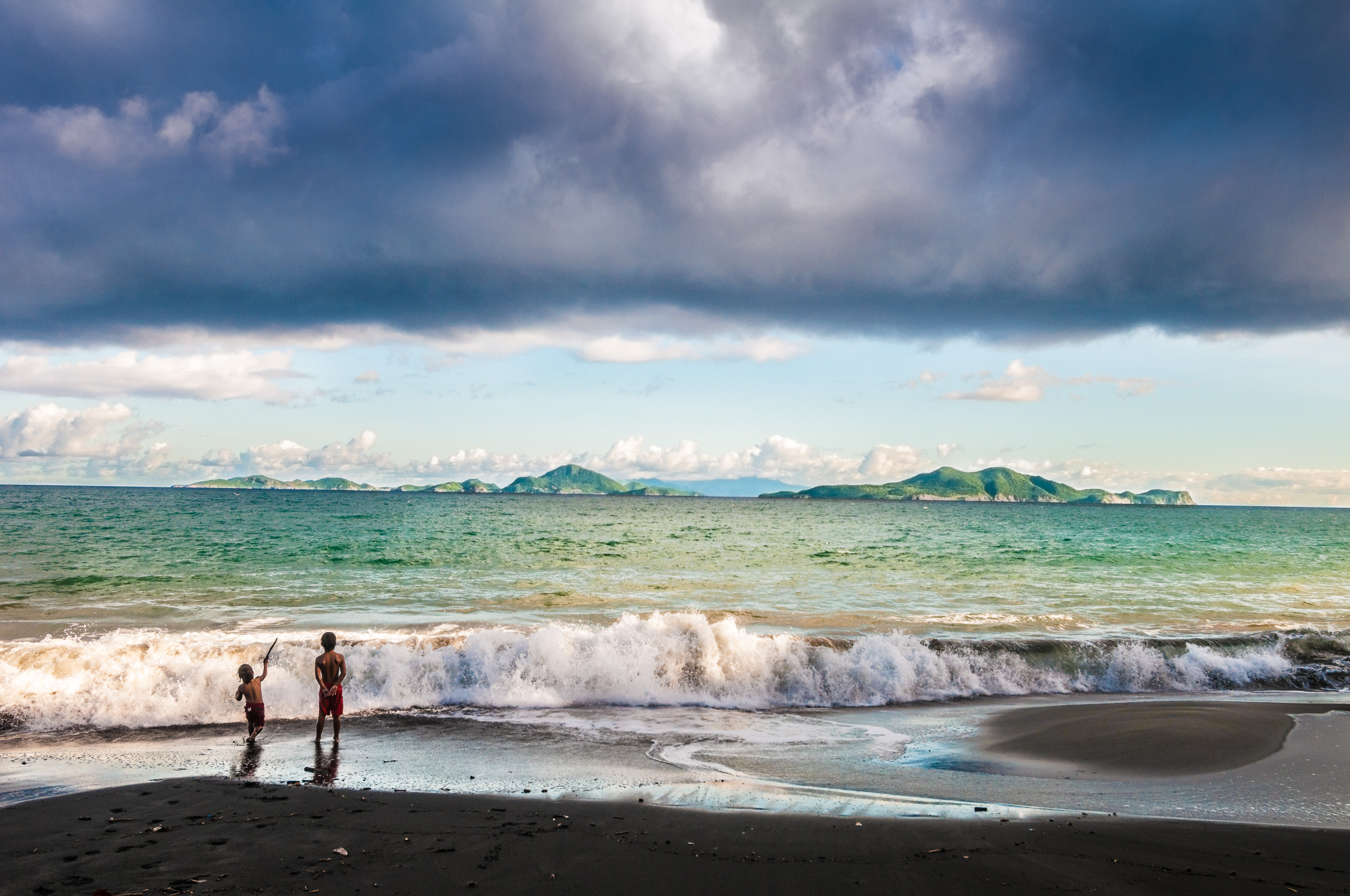 France, Caraïbes, Petites Antilles, Guadeloupe, Basse-Terre, Trois Rivières, 2 enfants jouent sur la plage de sable noir de Grande Anse, vue sur l'archipel des Saintes et l'île de La Dominique en arrière-plan // France, Caribbean, Lesser Antilles, Guadeloupe, Basse-Terre, Trois Rivières, 2 children play on the black sand beach of Grande Anse, view of Les Saintes archipelago and Dominica island in background